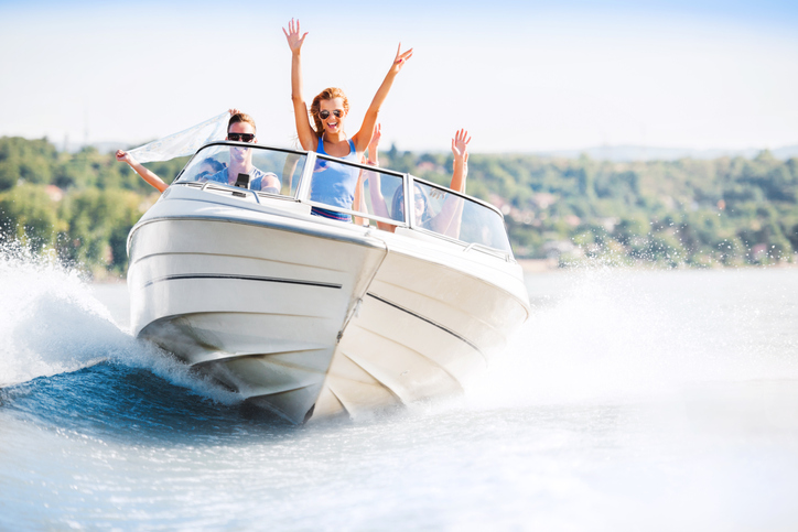 Group of young people with raised hands enjoying in a speedboat ride.