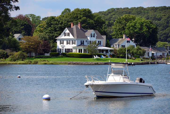 Luxury house on the water's edge - boat and trees.