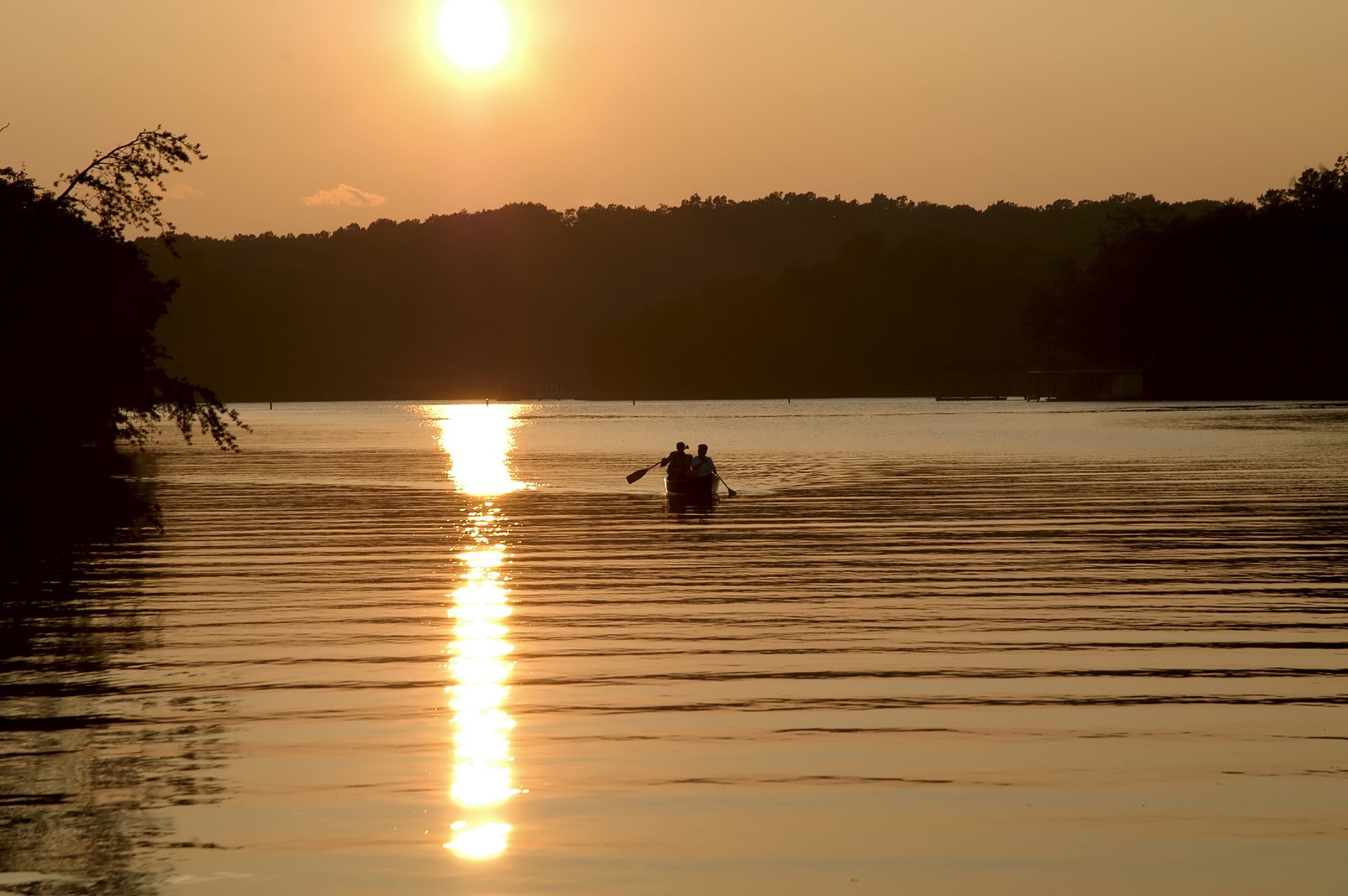 sunset view of people rowing their small boat on the lake