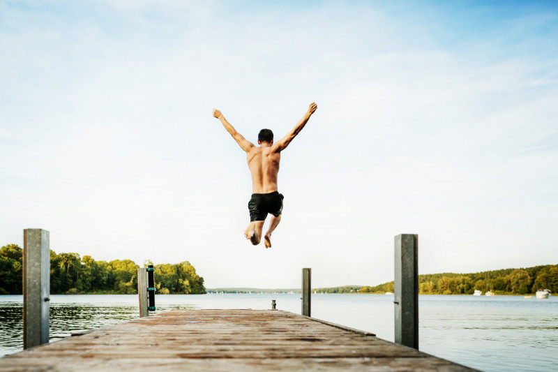 A guy jumping at a lake