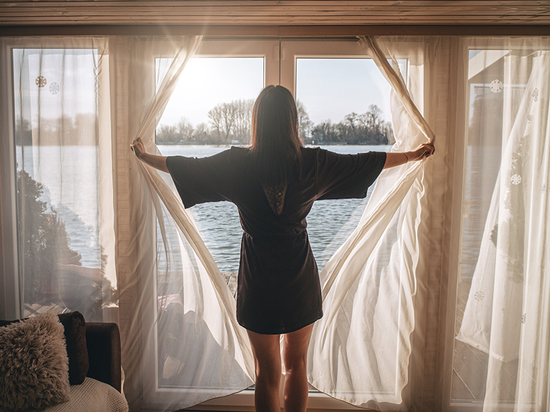 woman opening curtains