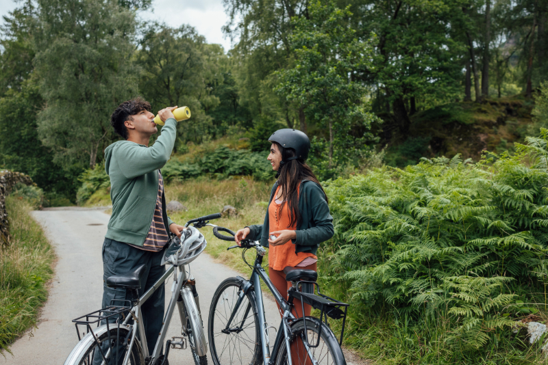 man drinking water with his girl and bicycle