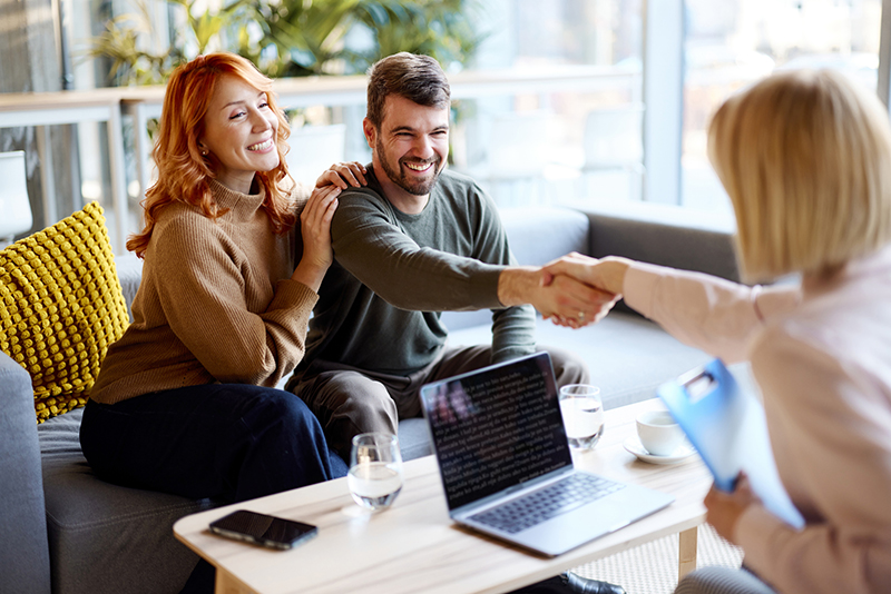 Young happy couple reached a successful deal with their real estate agent during a casual meeting in the office.